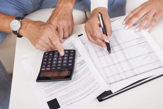 Dois empreendedores colaborando em cálculos com uma calculadora e papéis