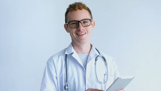 Um médico com um sorriso no rosto segurando um tablet nas mãos.