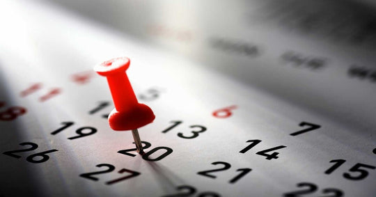 Um alfinete vermelho marcando o dia 20 em um calendário.