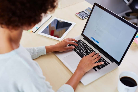 Mulher sentada em uma mesa, digitando em seu laptop. Serviço de atendimento virtual da Receita Federal