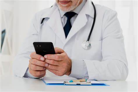 Profissional da saúde trabalha em sua mesa utilizando seu smartphone